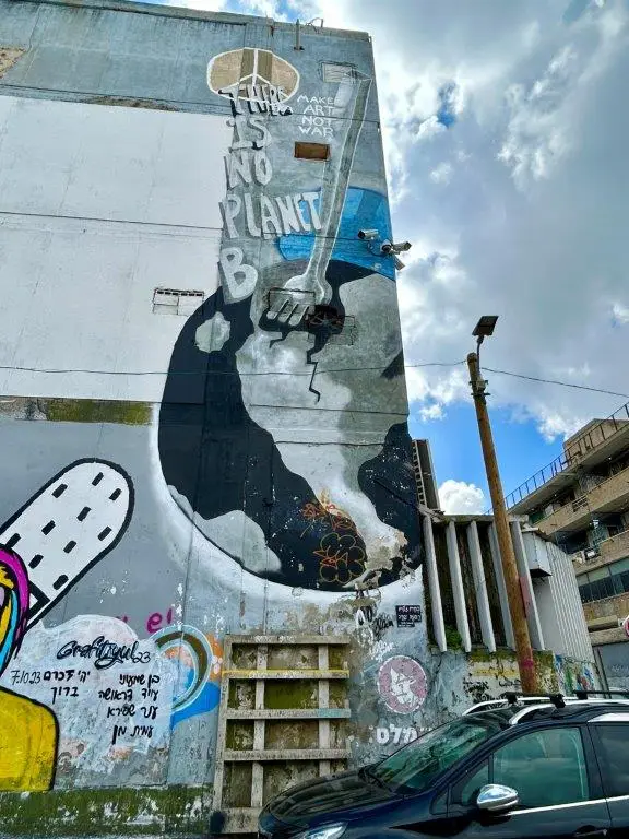 גרפיטי על קיר ענק בקרית המלאכה של כדור הארץ ובתוכו נעוץ מזלג