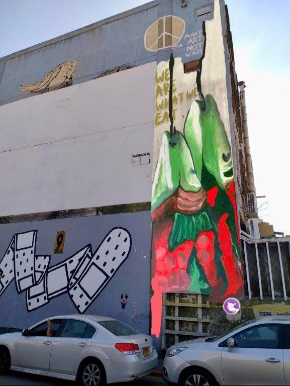 הדמיה של ציור גרפיטי של דגים מתים עם קרס בפה שלהם על בנין בקרית המלאכה
