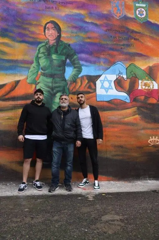 משפחתה של שיר אל פור חיים עומדת ליד ציור הגרפיטי שלה